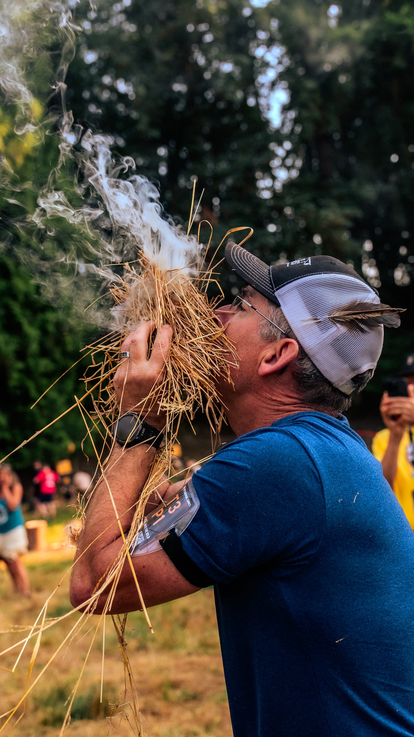 A competitor blowing a tinder bundle into smoke during the fire challenge